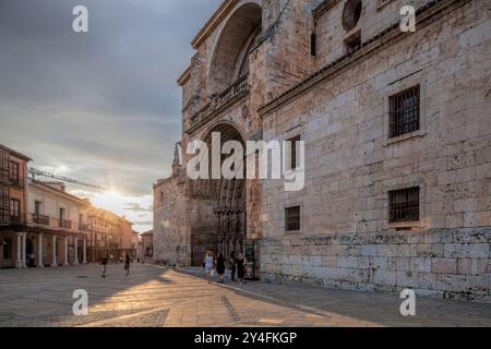 La grandiosa facciata della cattedrale di El Burgo de Osma si illumina magnificamente durante il tramonto, illuminando l'architettura in pietra e le strade circostanti. Foto Stock