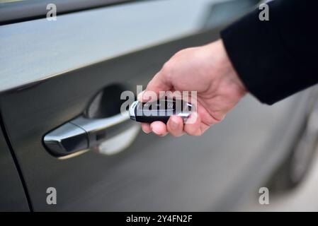 Una femmina preme il sistema di allarme per auto con telecomando Foto Stock