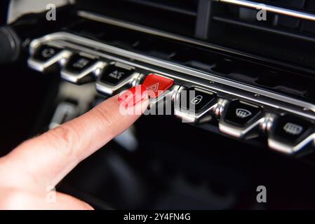 Pulsante di avvertimento di emergenza auto triangolare rosso femmina premuto Foto Stock