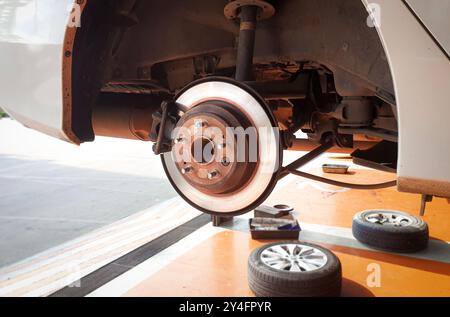 Impianto frenante posteriore con freni a disco e pinze , sollevamento di un'auto senza ruote per la riparazione in un'officina di riparazione auto , concetto di riparazione auto Foto Stock