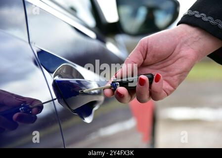 Una femmina preme il sistema di allarme per auto con telecomando Foto Stock