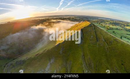 Il sole che sorge illumina il lato della nuvola di Thorpe mentre alcuni nebbiosi amano attraverso la valle sottostante, Dovedale, nel Peak District Derbyshire, Regno Unito. Foto Stock