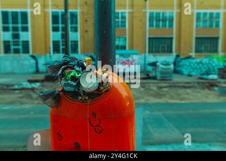 Un bidone di spazzatura troppo pieno con molta spazzatura che sporge fuori dall'apertura, pulizia della città, bidone di spazzatura pieno di rifiuti urbani Foto Stock