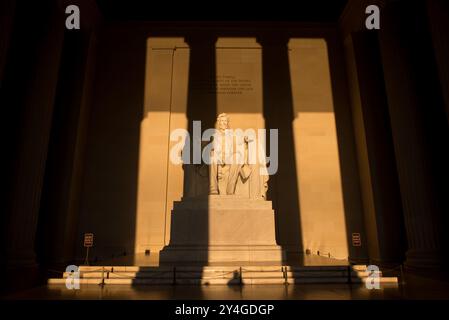 WASHINGTON DC, Stati Uniti: La statua di Abraham Lincoln all'interno del Lincoln Memorial è illuminata dalla luce naturale dorata del sole subito dopo l'alba. Questo effetto luminoso, visibile intorno all'equinozio primaverile e autunnale, esalta la grandezza del monumento mentre il sole splende attraverso l'ingresso orientale. Il Lincoln Memorial, situato sul National Mall, è uno dei monumenti più iconici degli Stati Uniti. NB: Il colore e l'illuminazione sono naturali. Foto Stock