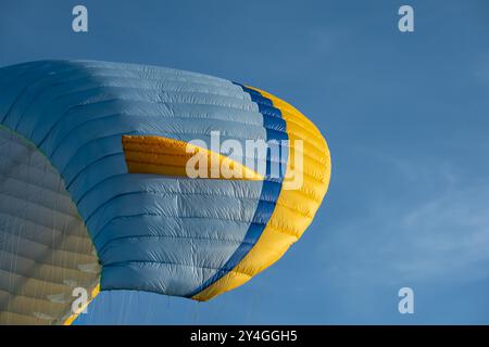 Ala di parapendio in aria contro il cielo blu. Il parapendio vola nel cielo. Primo piano dell'ala del paracadute. Attività sportive paracadutismo ascensionale sport estremi e viaggi Foto Stock