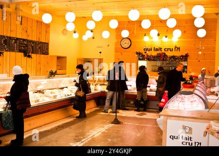 Jean-Talon Market Cheese Selection Montreal Canada // MONTREAL, Canada - i clienti possono sfogliare una selezione di formaggi in una moderna gelateria nel Jean-Talon Market, uno dei mercati pubblici più vecchi e grandi di Montreal. Fondato nel 1933, il Jean-Talon Market si trova nel quartiere di Little Italy ed è noto per la sua ampia varietà di prodotti locali, negozi di specialità alimentari e prodotti artigianali. Il mercato rimane una destinazione popolare sia per la gente del posto che per i turisti alla ricerca di cibi freschi e regionali e specialità del Quebec. Foto Stock