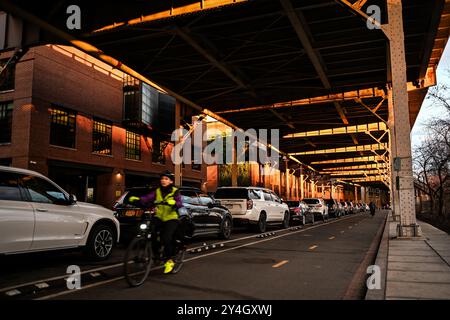 Whitehurst Freeway Bike Lanes Georgetown Washington DC // WASHINGTON DC - Un ciclista viaggia lungo le piste ciclabili dedicate che corrono sotto la Whitehurst Freeway nello storico quartiere Georgetown di Washington DC. La superstrada sopraelevata Whitehurst, costruita nel 1949, funge da strada principale che collega K Street al Key Bridge. Queste piste ciclabili protette fanno parte della rete Capital Crescent Trail, fornendo ai ciclisti un percorso più sicuro attraverso questo trafficato corridoio urbano. Georgetown, uno dei quartieri più antichi di Washington, presenta un mix di architettura storica e negozi Foto Stock