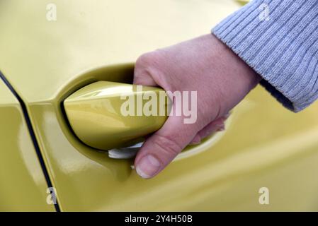 Una donna apre la porta di un'autovettura Foto Stock