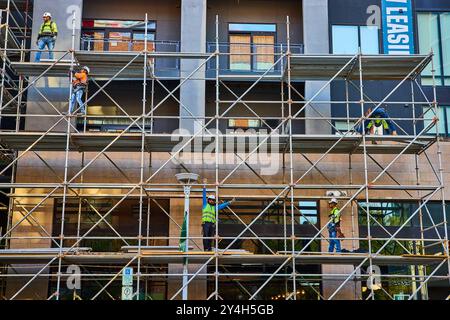 Lavoratori delle costruzioni urbane su ponteggi in movimento Foto Stock