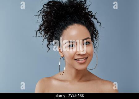 Giovane donna di bellezza naturale che guarda la fotocamera su sfondo grigio Foto Stock