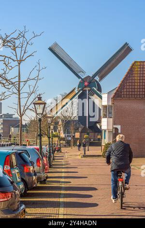 Leida, Paesi Bassi - 5 marzo 2022: Un uomo attraversa il Kort Galgewater in bicicletta verso il mulino a vento De Put a Leida in una giornata di sole Foto Stock