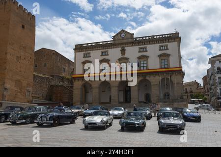 Scena cittadina con diverse auto d'epoca di fronte a edifici storici e bandiere in una giornata di sole, Municipio, Ayuntamiento, auto d'epoca, Plaza Mayor, Cace Foto Stock