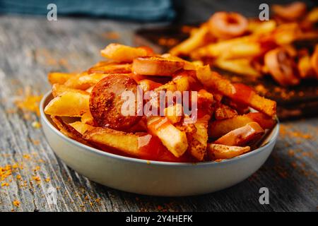 primo piano di un piatto con alcuni ribes a fette serviti con patatine, condite con il tipico ketchup di curry e curry in polvere, come è tipico in germania Foto Stock