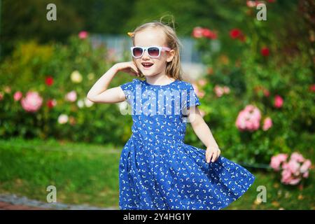 Adorabile ragazza in età prescolare che si diverte in un parco verde in una giornata d'estate Foto Stock