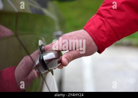 Un uomo apre la porta di un'autovettura Foto Stock