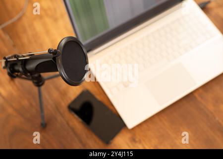 Configurazione podcasting con microfono, computer portatile e smartphone su scrivania in legno, spazio per le copie Foto Stock