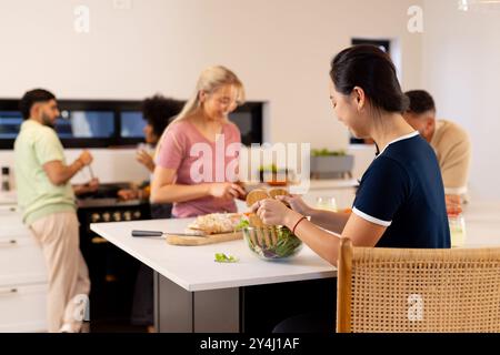 Preparare il cibo insieme, un gruppo di giovani e diversi amici che si divertono in cucina Foto Stock