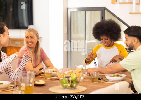 Pranza insieme, un gruppo di giovani e diversi amici gustando un pasto a casa Foto Stock