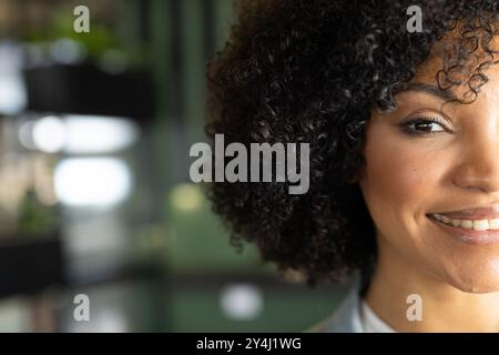 Donna sorridente con capelli ricci in un ambiente di lavoro, ritratti in primo piano, spazio per le copie Foto Stock