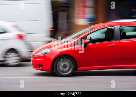 Auto rossa compatta che si muove velocemente su una strada trafficata nel centro di Belo Horizonte, Brasile Foto Stock