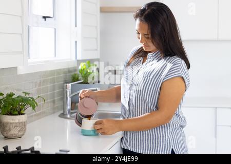 Versare caffè dalla stampa francese, donna che si diverte la routine mattutina in cucina Foto Stock