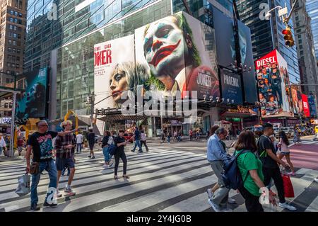 Orde di persone attraversano West 42nd Street sotto pubblicità per la Warner Bros. PicturesÕ ÒJoker: Folie ‡ DeuxÓ domenica 15 settembre 2024. Il film, interpretato da Joaquin Phoenix e Lady Gaga, sarà distribuito il 4 ottobre 2024 (© Richard B. Levine) Foto Stock