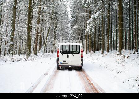 Camper che guida su una strada attraverso una foresta innevata in inverno, vacanze avventurose e stile di vita nei boschi, autostrada scivolosa Foto Stock