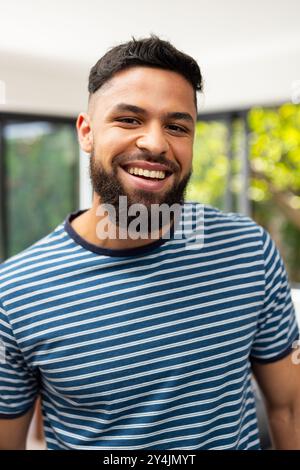 Giovane sorridente in camicia a righe che si diverte con gli amici al chiuso Foto Stock