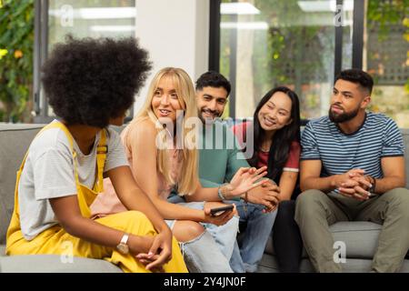 Gruppo di giovani amici seduti sul divano, a parlare e a divertirsi insieme Foto Stock