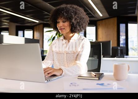 Lavoro in ufficio, donna che utilizza un notebook e scrive in blocco note, concentrandosi sulle attività Foto Stock