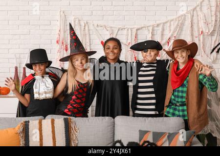 Bambini carini e felici in diversi costumi vestiti per la festa di Halloween a casa Foto Stock