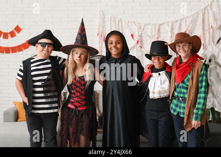 Bambini carini e felici in diversi costumi vestiti per la festa di Halloween a casa Foto Stock