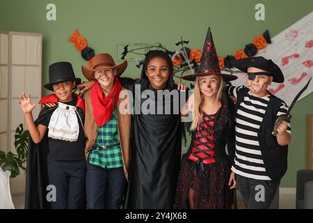 Bambini carini e felici in diversi costumi vestiti per la festa di Halloween a casa Foto Stock