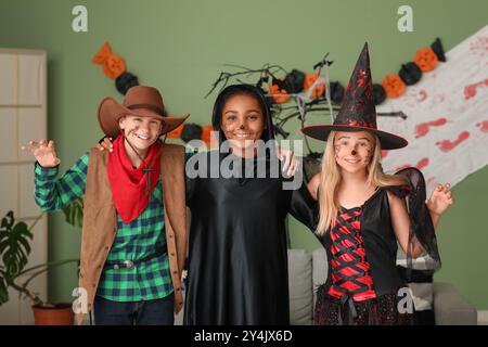 Bambini carini e felici in diversi costumi vestiti per la festa di Halloween a casa Foto Stock