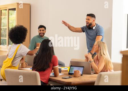 Un gruppo di giovani amici che ridono e si divertono mentre lavorano su notebook, avviano un'attività Foto Stock