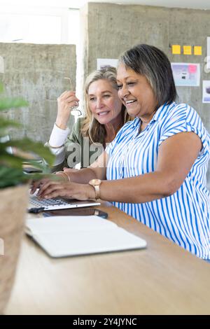 In ufficio, colleghi donne anziane multirazziali che collaborano con un notebook Foto Stock