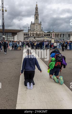 I pellegrini strisciano in ginocchio verso la Basilica di nostra Signora del Rosario di Fatima, in Portogallo, dove la Vergine Maria apparve a tre pastorelli. Foto Stock