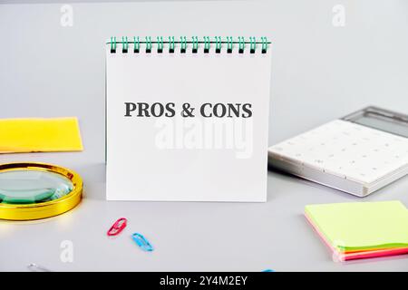 Messaggi DI PRO e CONTRO su un notebook bianco su sfondo grigio in una composizione con accessori business, vista frontale Foto Stock