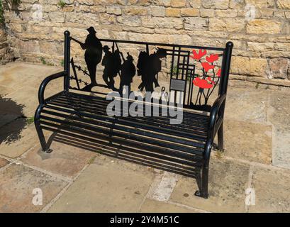 Panchina commemorativa delle guerre mondiali e dei conflitti con papaveri e sagome da soldato. Stamford, Lincolnshire, Inghilterra. Foto Stock