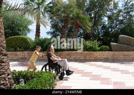 Nonna in sedia a rotelle e nipote che fa una passeggiata Foto Stock