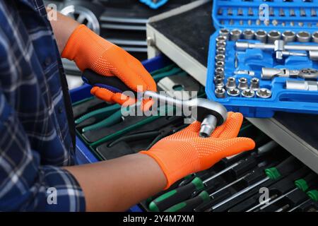 Meccanico automatico con chiave dinamometrica e utensili diversi presso l'officina di riparazione di automobili, primo piano Foto Stock