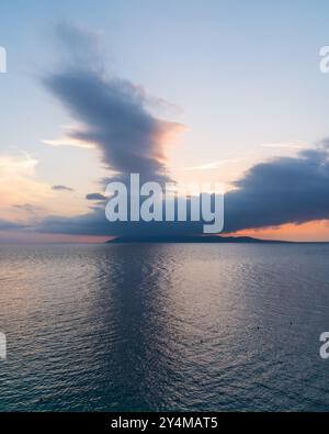 Tramonto sul mare. Acqua scura sul mare. Un'isola all'orizzonte. Nuvole al tramonto nel cielo. La bellezza del paesaggio marino. Foto Stock