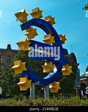 Francoforte, Hess, Germania - 2024, 23 luglio: Foto della cena del grande simbolo dell'euro a Francoforte tra aree verdi su un cielo limpido e soleggiato Foto Stock