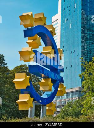 Francoforte, Hess, Germania - 2024, 23 luglio: Foto della cena del grande simbolo dell'euro a Francoforte tra aree verdi su un cielo limpido e soleggiato Foto Stock