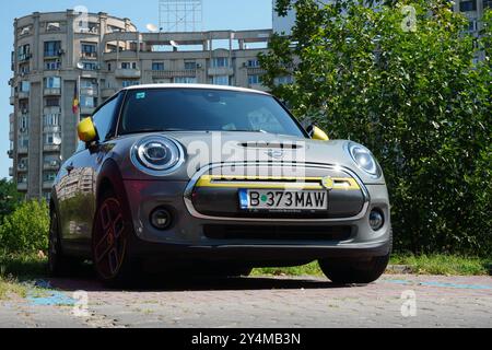 Bucarest, Romania - 28 luglio 2024: Mini Cooper se grigio elettrico con carina auto gialla nel parcheggio in zona residenziale Foto Stock