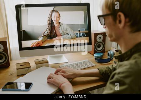 Vista a spalla di un uomo irriconoscibile che legge un libro in Braille seduto al tavolo di lavoro Foto Stock