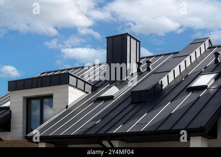 Primo piano del tetto posteriore della casa con cuciture e dispositivi di fissaggio. Moderna lamiera di copertura in acciaio zincato con nervature. Pannello in metallo nero dallo stile classico Foto Stock