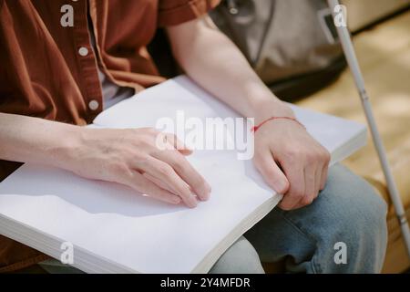 Primo piano medio di mani maschili irriconoscibili che toccano la pagina con il sistema di scrittura Braille Foto Stock