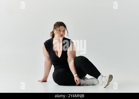 Una donna elegante e di grandi dimensioni si posa con sicurezza su uno sfondo chiaro. Foto Stock