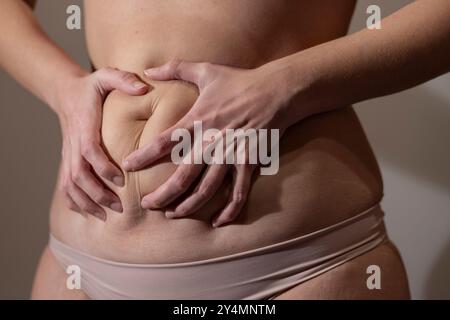 Primo piano di un corpo femminile che le stringe la pancia. Messa a fuoco morbida Foto Stock